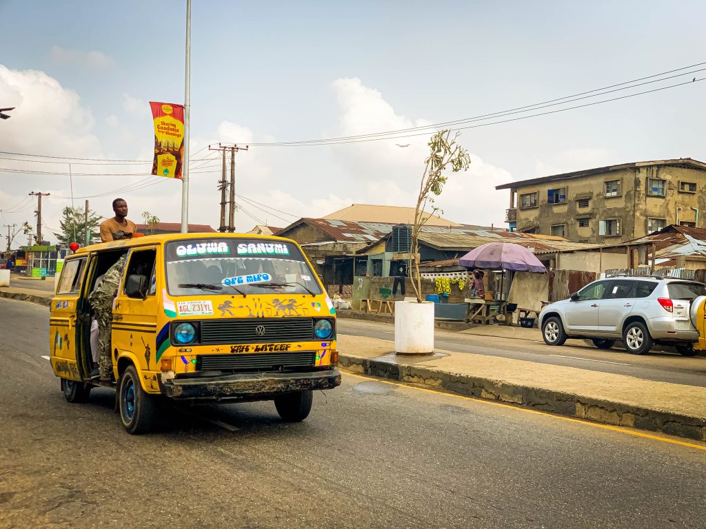 Vibrant street scene featuring a yellow danfo bus in Lagos, Nigeria during the day.